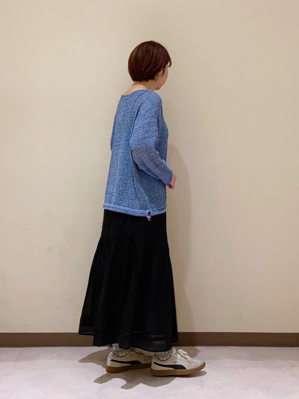 ブルー系のニット/セーター、ブラック系のスカートを着用したレディースの春コーディネートの3枚目の写真