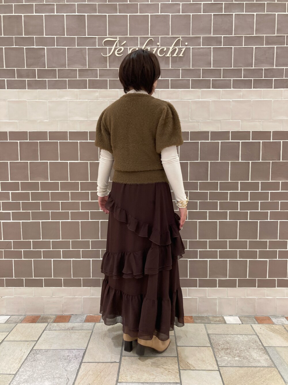 ブラウン系のニット/セーター、ブラウン系のスカート、ホワイト系のTシャツ/カットソーを着用したレディースの秋コーディネートの4枚目の写真