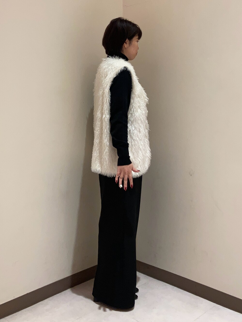 ブラック系のニット/セーター、ホワイト系のベスト、ブラック系のパンツを着用したレディースの秋コーディネートの2枚目の写真