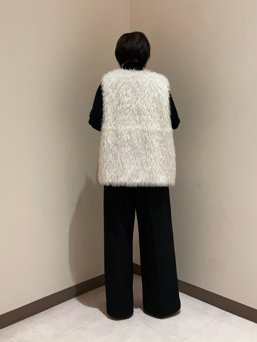 ブラック系のニット/セーター、ホワイト系のベスト、ブラック系のパンツを着用したレディースの秋コーディネートの3枚目の写真