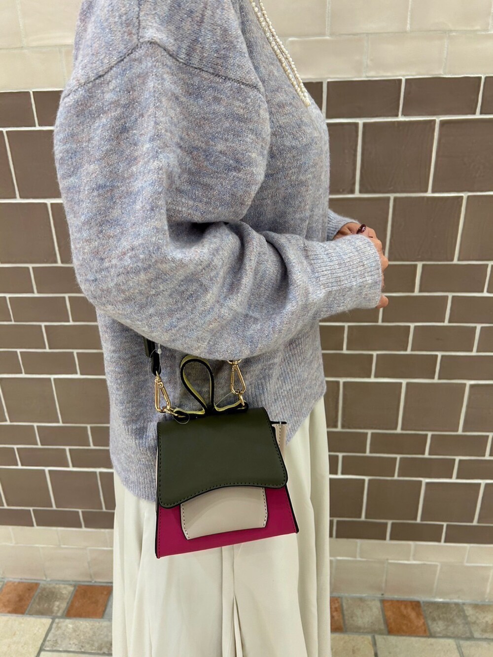 パープル系のニット/セーター、ピンク系のハンドバッグ、ホワイト系のスカートを着用したレディースの冬コーディネートの2枚目の写真