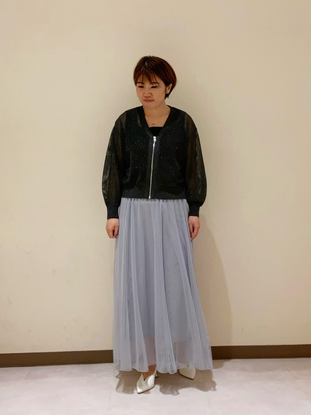 グレー系のカーディガン/ボレロ、グレー系のスカート、ブラック系のタンクトップを着用したレディースの春コーディネートの2枚目の写真