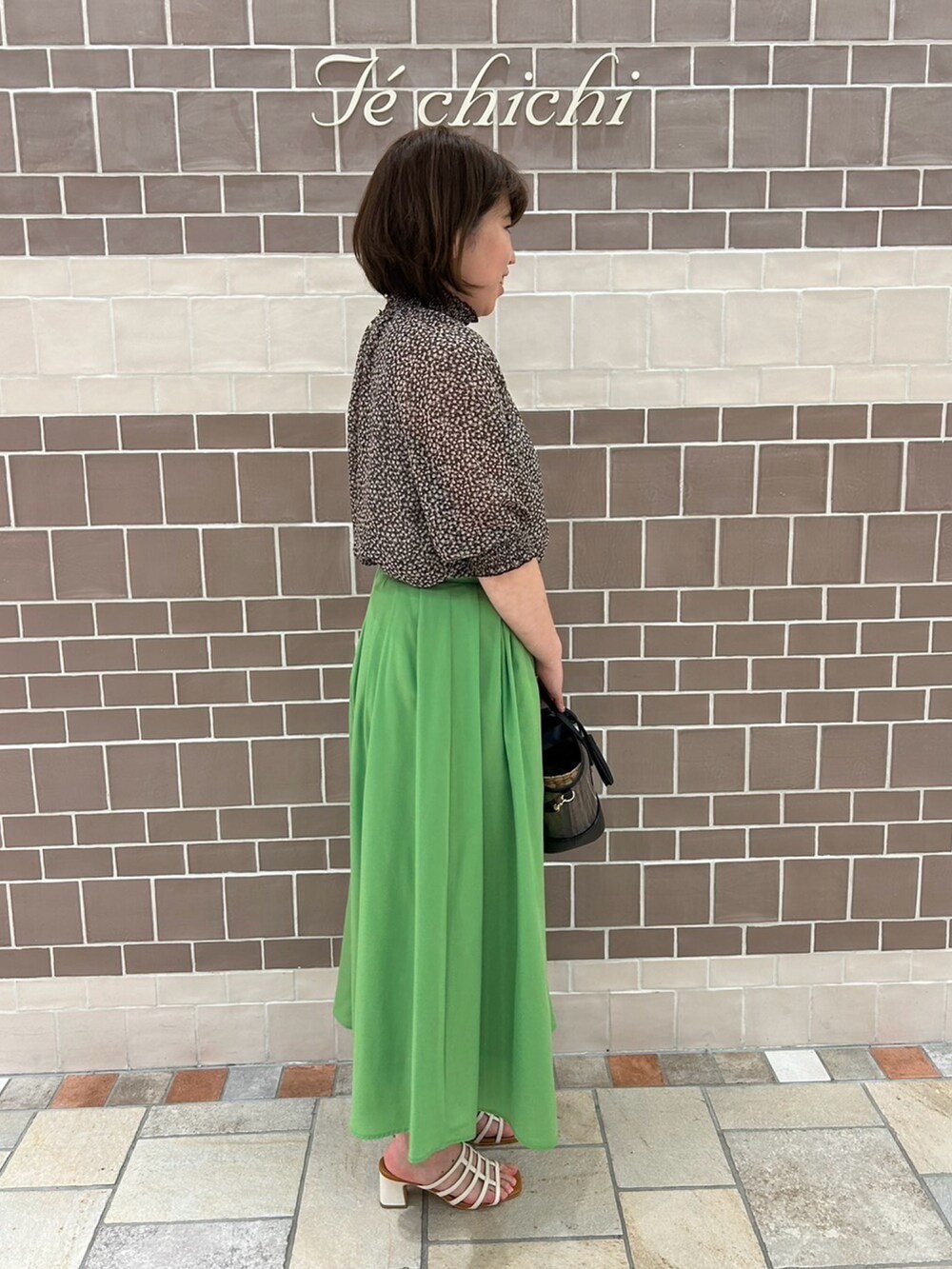 グリーン系のスカート、ホワイト系のサンダル、グレー系のシャツ/ブラウスを着用したレディースの春コーディネートの2枚目の写真