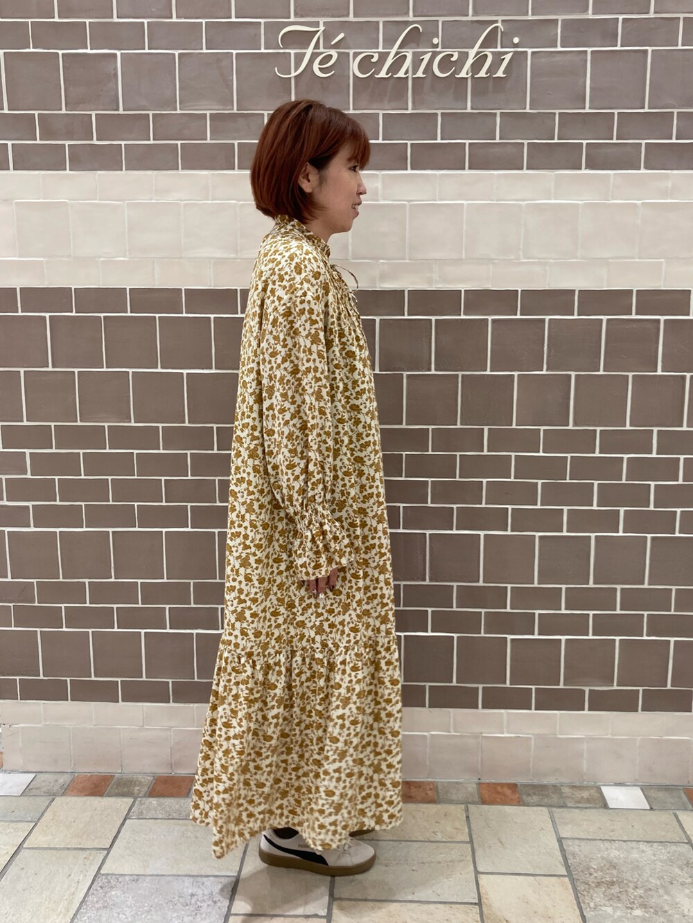 ベージュ系のワンピースを着用したレディースの秋コーディネートの2枚目の写真