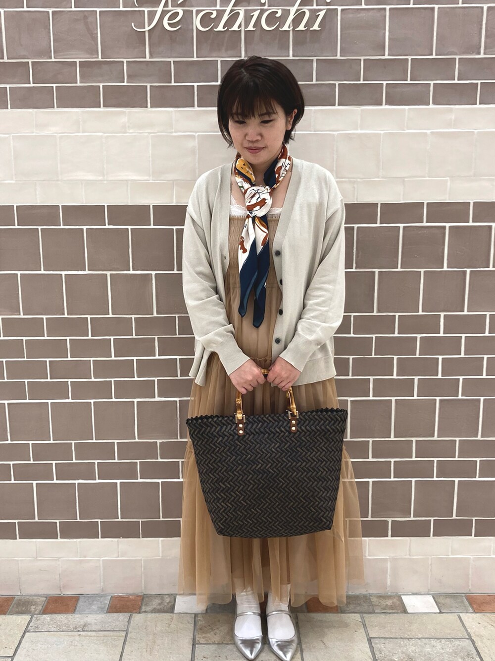 ブラウン系のワンピース、シルバー系のカーディガン/ボレロ、ブラウン系のトートバッグを着用したレディースの春コーディネートの2枚目の写真
