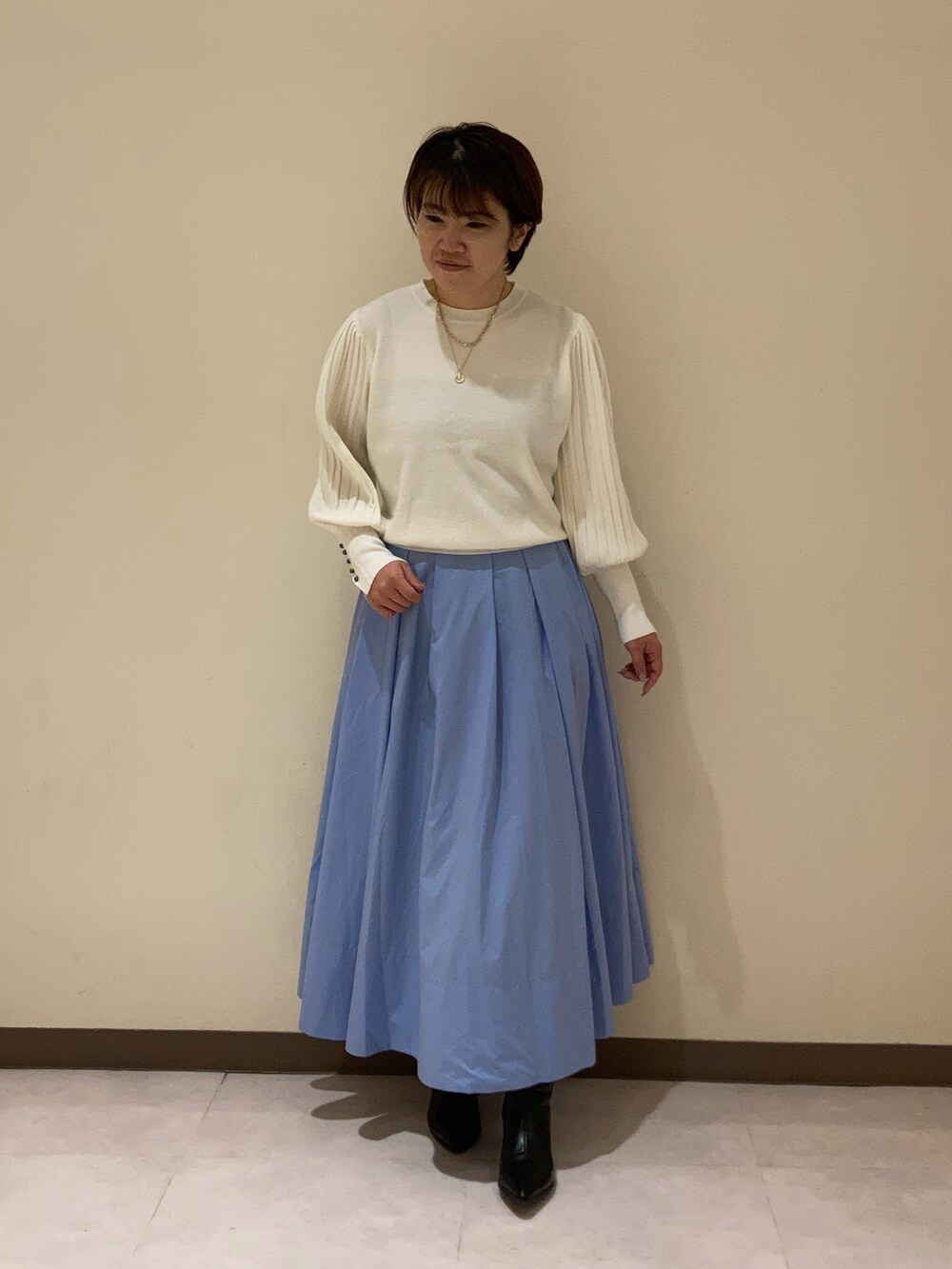 ホワイト系のニット/セーター、ブルー系のスカートを着用したレディースの冬コーディネートの2枚目の写真