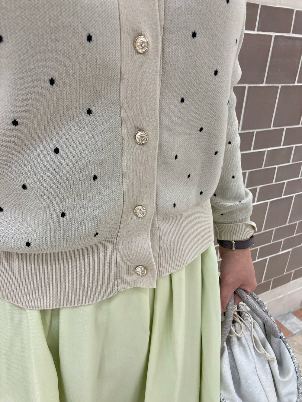 ホワイト系のカーディガン/ボレロ、イエロー系のスカート、シルバー系のハンドバッグを着用したレディースの冬コーディネートの3枚目の写真