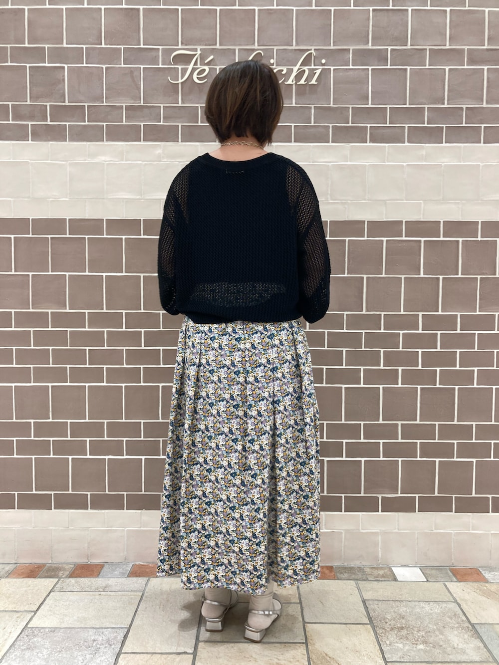 ブラック系のニット/セーター、ブルー系のスカート、シルバー系のパンプスを着用したレディースの春コーディネートの5枚目の写真