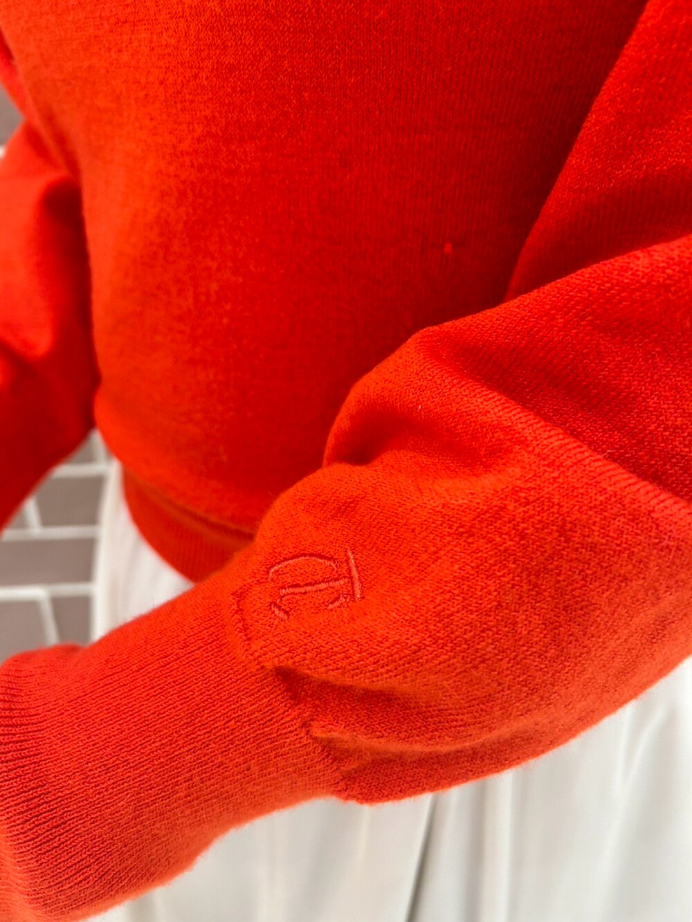 レッド系のニット/セーター、ゴールド系のハンドバッグ、ホワイト系のスカートを着用したレディースの冬コーディネートの2枚目の写真