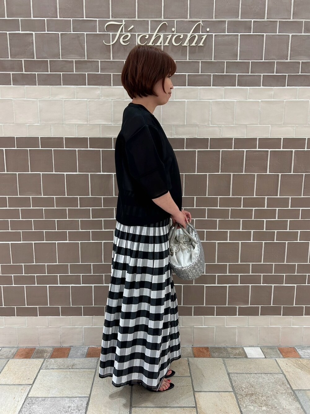 ブラック系のシャツ/ブラウス、ブラック系のスカート、シルバー系のハンドバッグを着用したレディースの春コーディネートの2枚目の写真