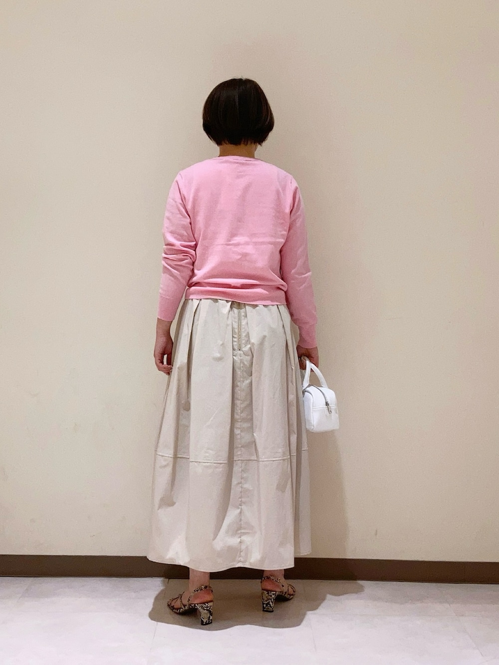 ピンク系のカーディガン/ボレロ、ベージュ系のスカート、ホワイト系のハンドバッグを着用したレディースの春コーディネートの3枚目の写真