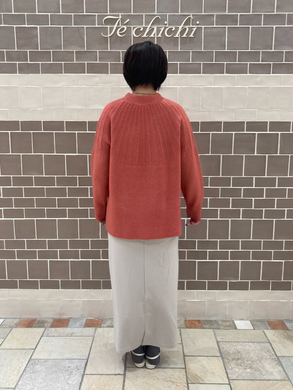 ピンク系のニット/セーター、ベージュ系のスカート、ホワイト系のパンプスを着用したレディースの秋コーディネートの3枚目の写真