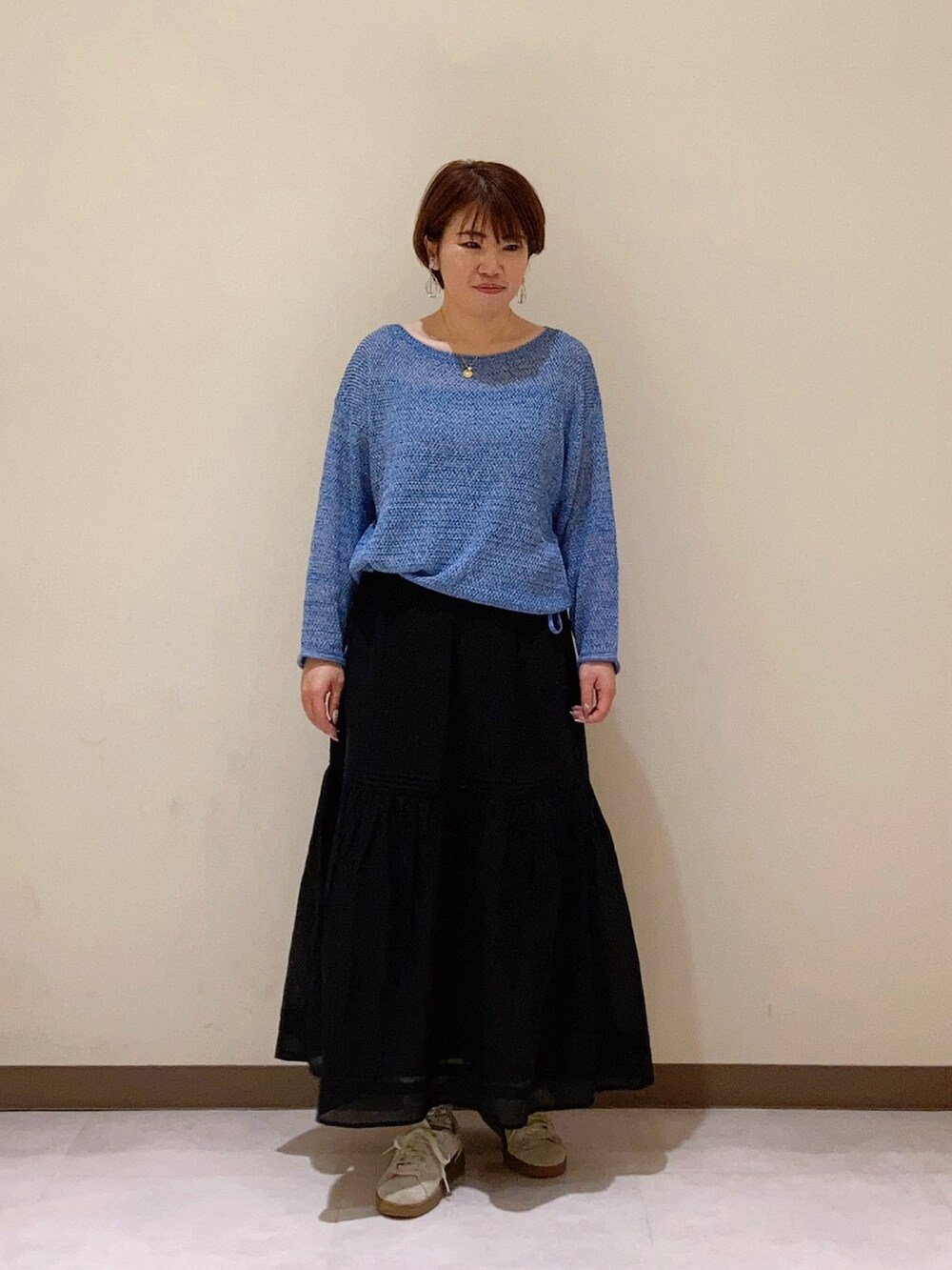 ブルー系のニット/セーター、ブラック系のスカートを着用したレディースの春コーディネートの2枚目の写真