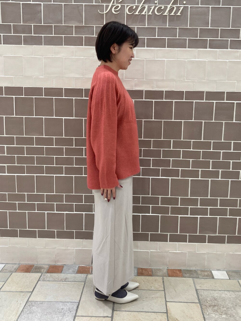 ピンク系のニット/セーター、ベージュ系のスカート、ホワイト系のパンプスを着用したレディースの秋コーディネートの2枚目の写真