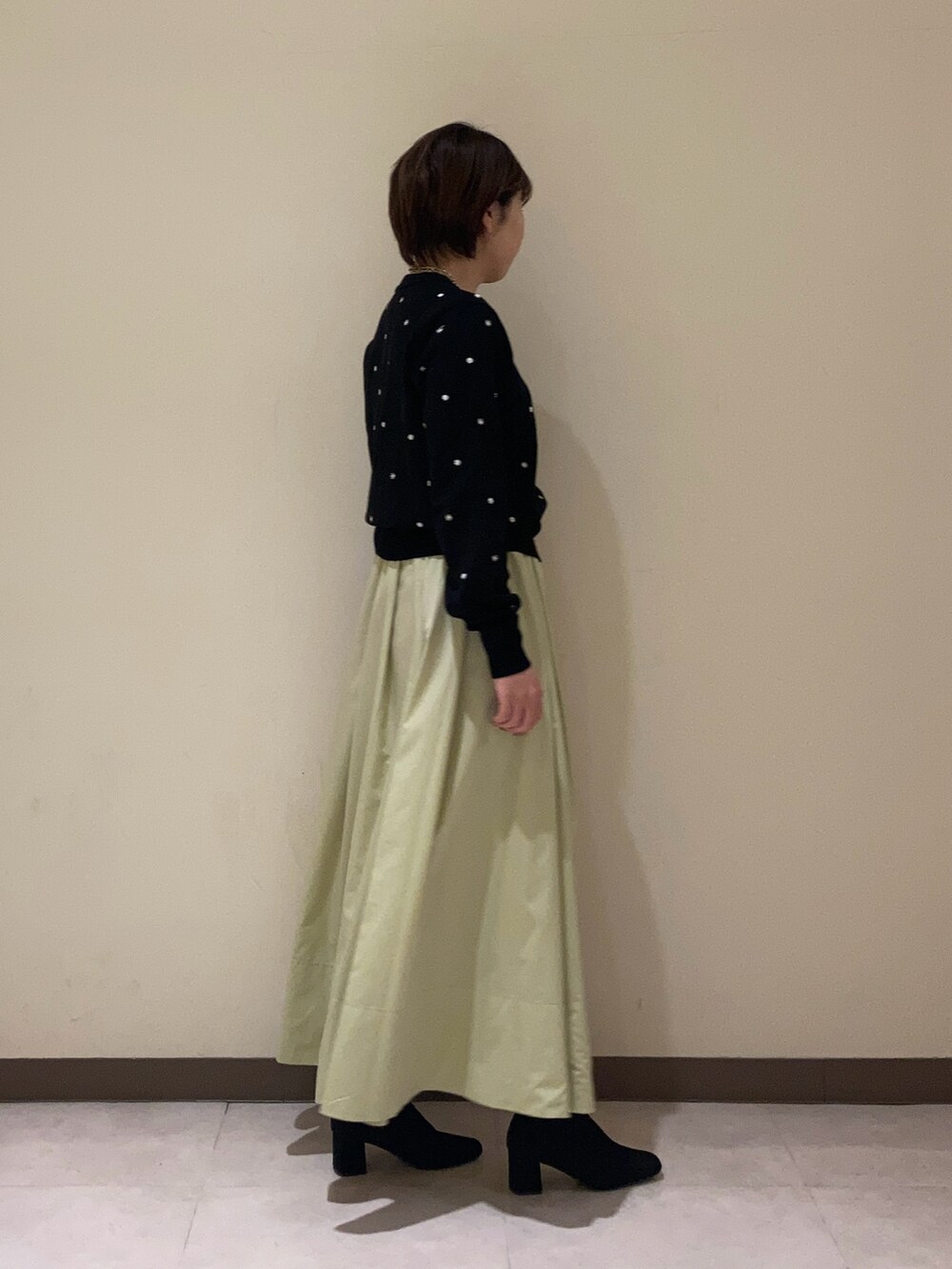 ブラック系のカーディガン/ボレロ、グリーン系のスカートを着用したレディースの冬コーディネートの2枚目の写真