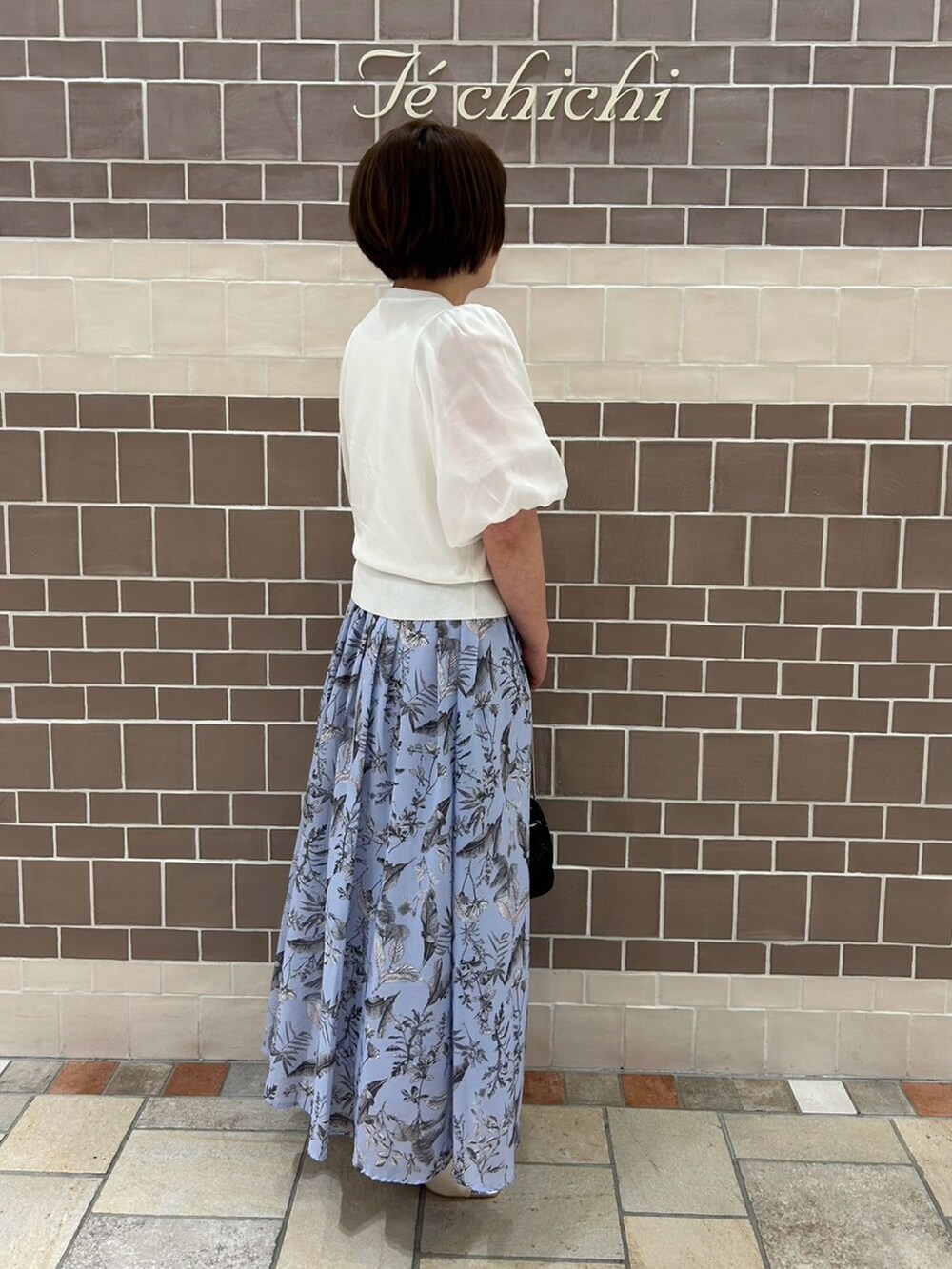 ホワイト系のニット/セーター、ブルー系のスカート、ホワイト系のサンダルを着用したレディースの春コーディネートの2枚目の写真