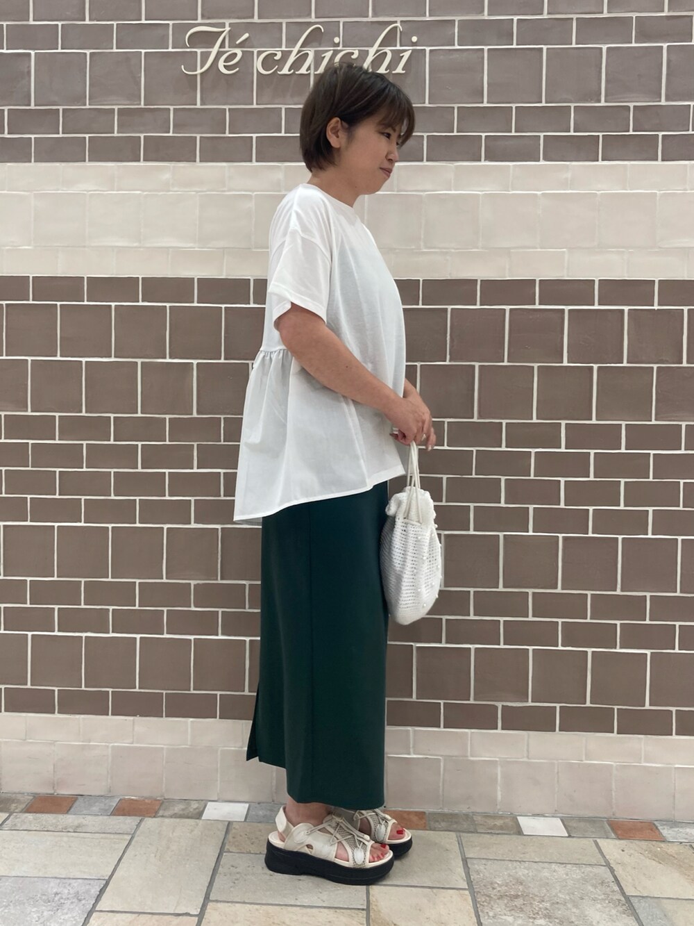 ホワイト系のTシャツ/カットソー、グリーン系のスカート、ホワイト系のハンドバッグを着用したレディースの夏コーディネートの2枚目の写真
