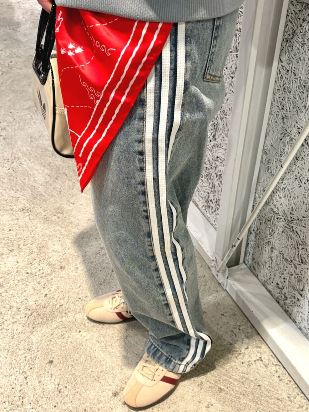 ブルー系のデニムジャケット、ブルー系のデニムパンツ、ベージュ系のショルダーバッグを着用したレディースの春コーディネートの3枚目の写真