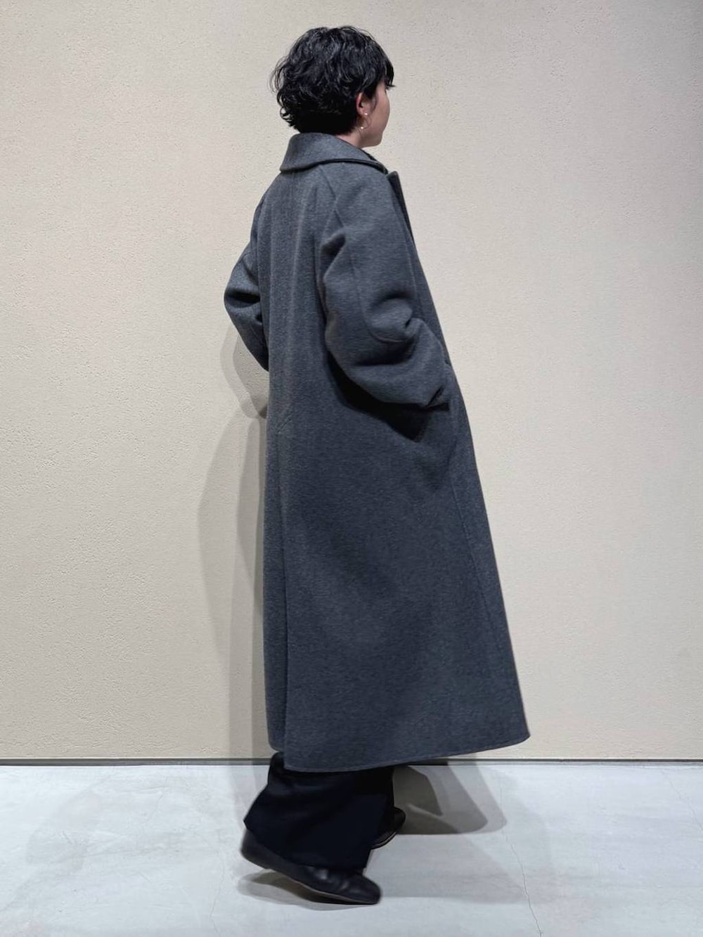 グレー系のチェスターコート、ブラック系のスラックス、ブラック系のニット/セーターを着用したレディースの冬コーディネートの4枚目の写真