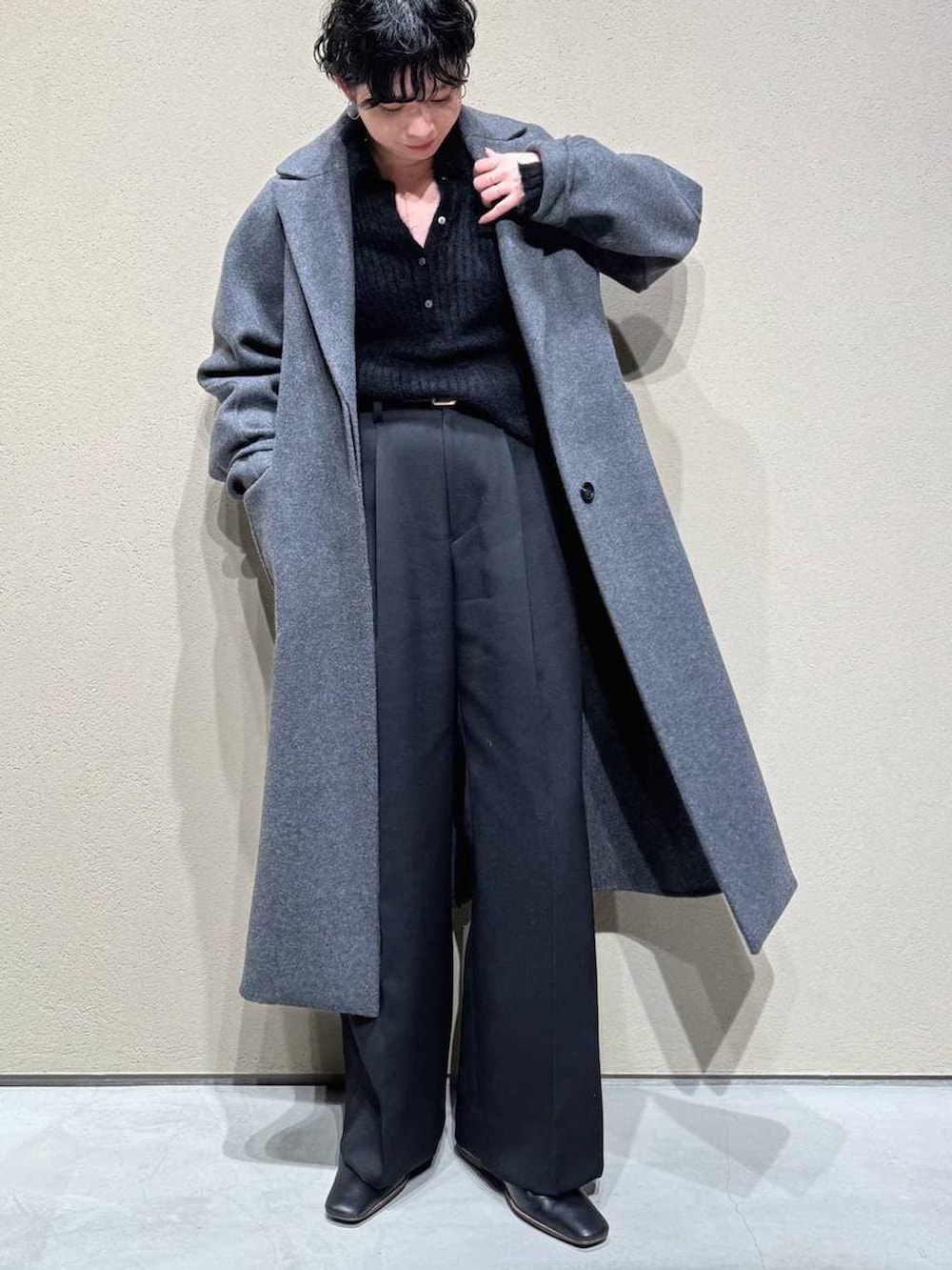 グレー系のチェスターコート、ブラック系のスラックス、ブラック系のニット/セーターを着用したレディースの冬コーディネートの2枚目の写真