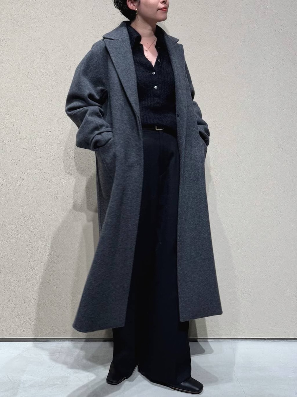 グレー系のチェスターコート、ブラック系のスラックス、ブラック系のニット/セーターを着用したレディースの冬コーディネートの3枚目の写真