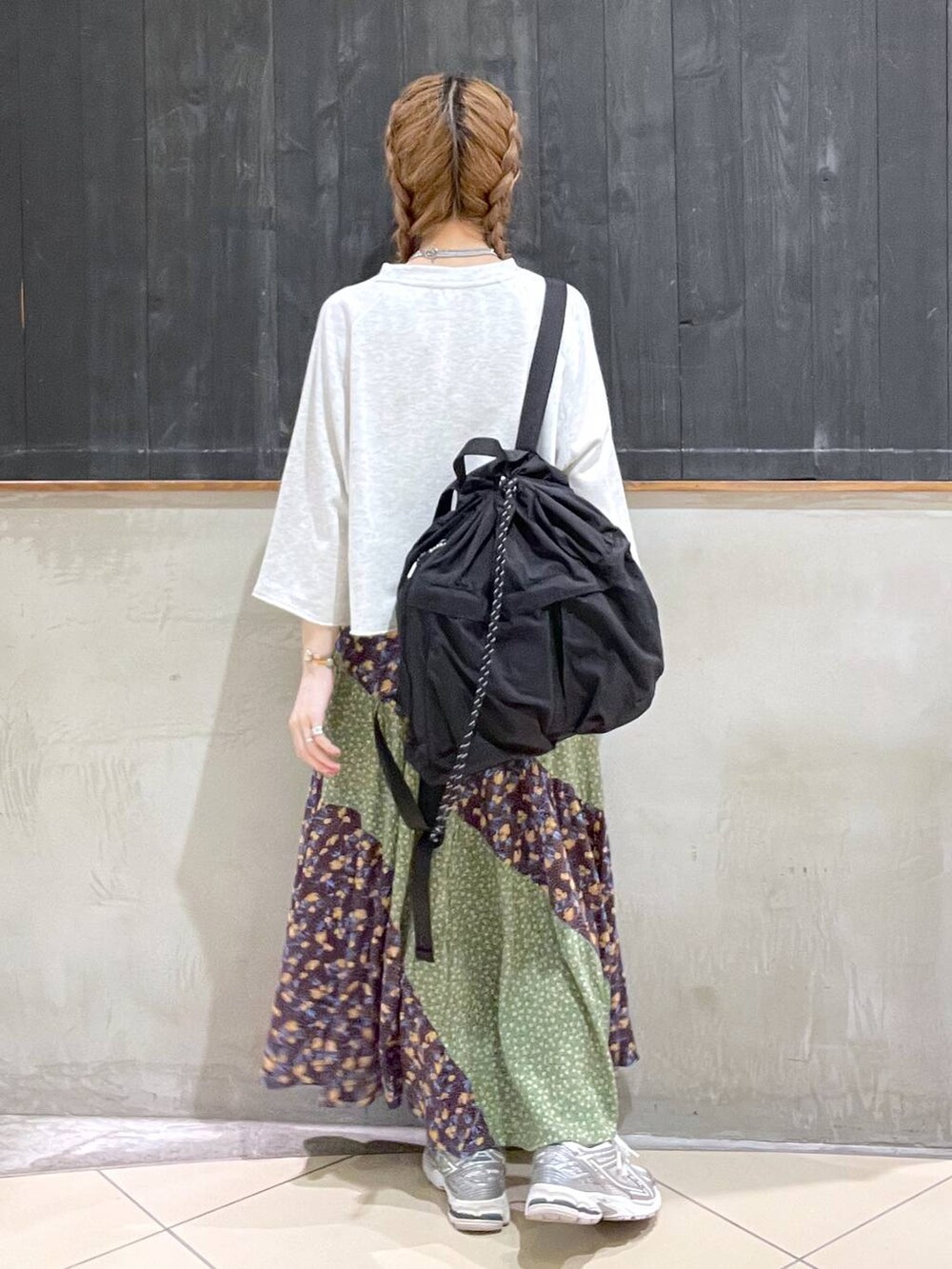 ブラック系のバックパック/リュック、ベージュ系のTシャツ/カットソー、グリーン系のスカートを着用したレディースの春コーディネートの3枚目の写真