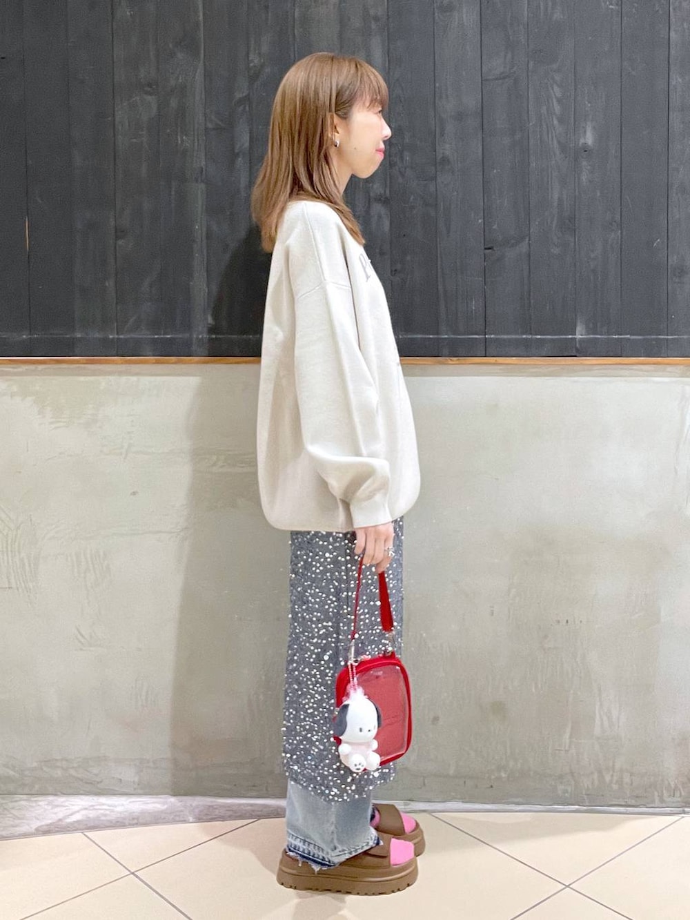 グレー系のスカート、レッド系のショルダーバッグ、ブルー系のデニムパンツを着用したレディースの春コーディネートの2枚目の写真