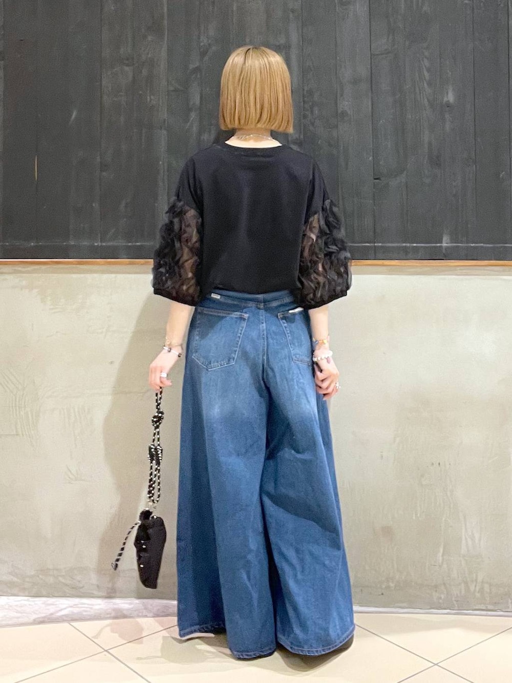 ブラック系のショルダーバッグ、ブルー系のデニムパンツ、ブラック系のサンダルを着用したレディースの夏コーディネートの3枚目の写真