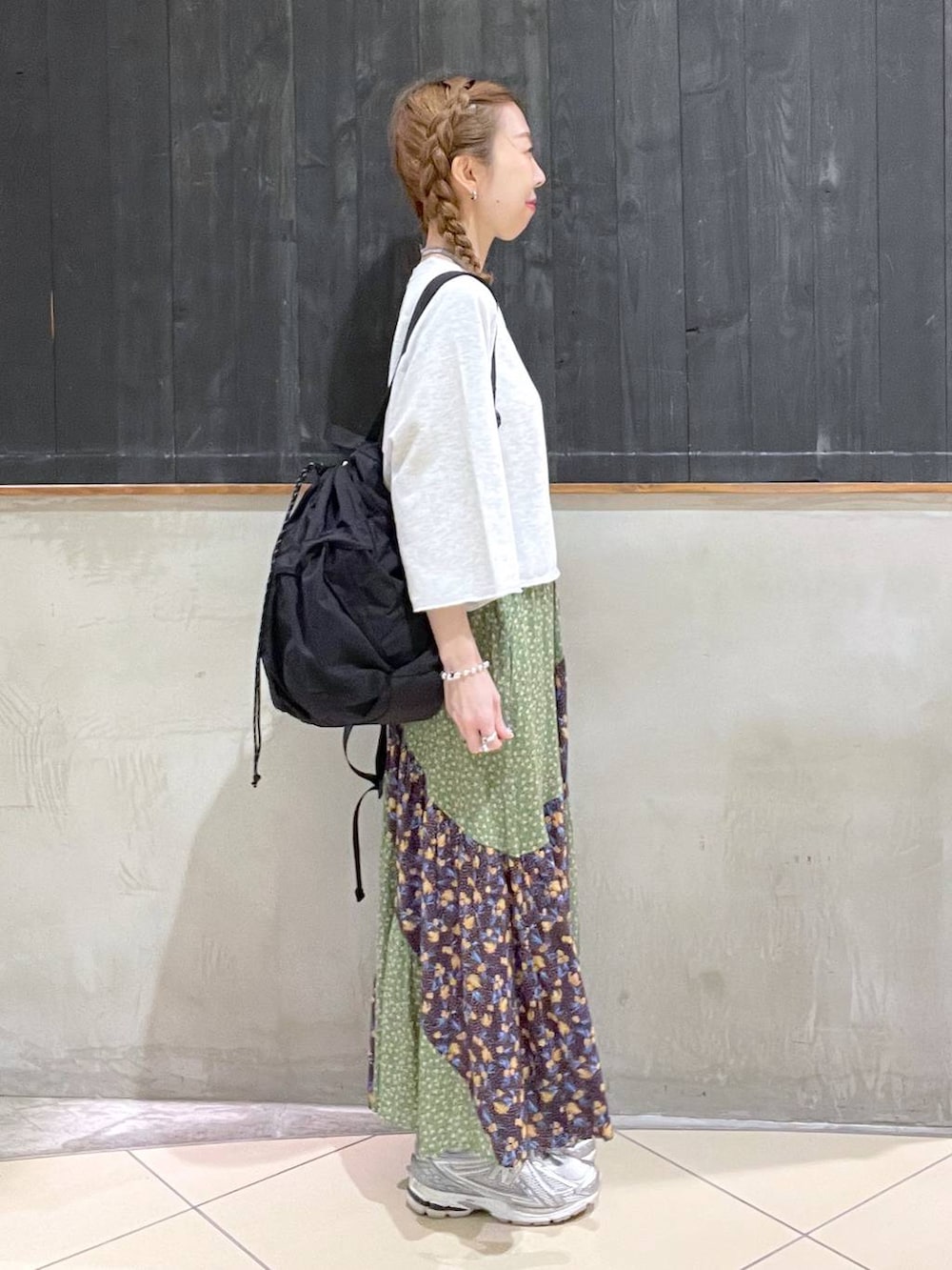 ブラック系のバックパック/リュック、ベージュ系のTシャツ/カットソー、グリーン系のスカートを着用したレディースの春コーディネートの2枚目の写真