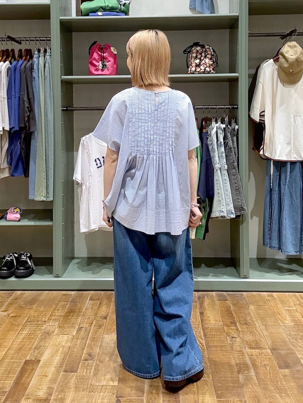 ブラック系のショルダーバッグ、ブルー系のデニムパンツ、ブラック系のサンダルを着用したレディースの夏コーディネートの3枚目の写真