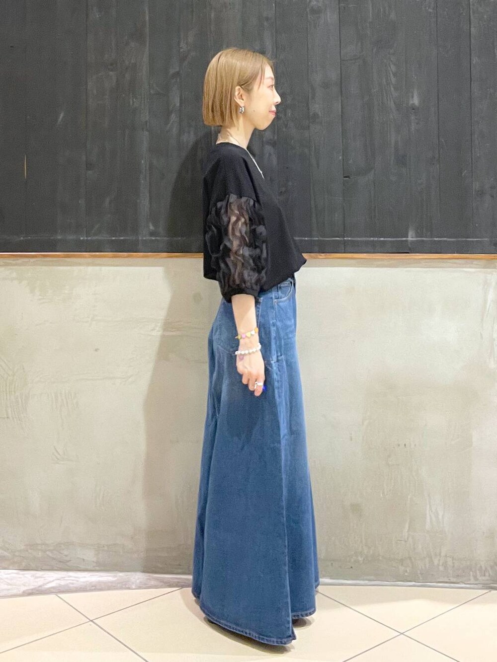 ブラック系のショルダーバッグ、ブルー系のデニムパンツ、ブラック系のサンダルを着用したレディースの夏コーディネートの2枚目の写真