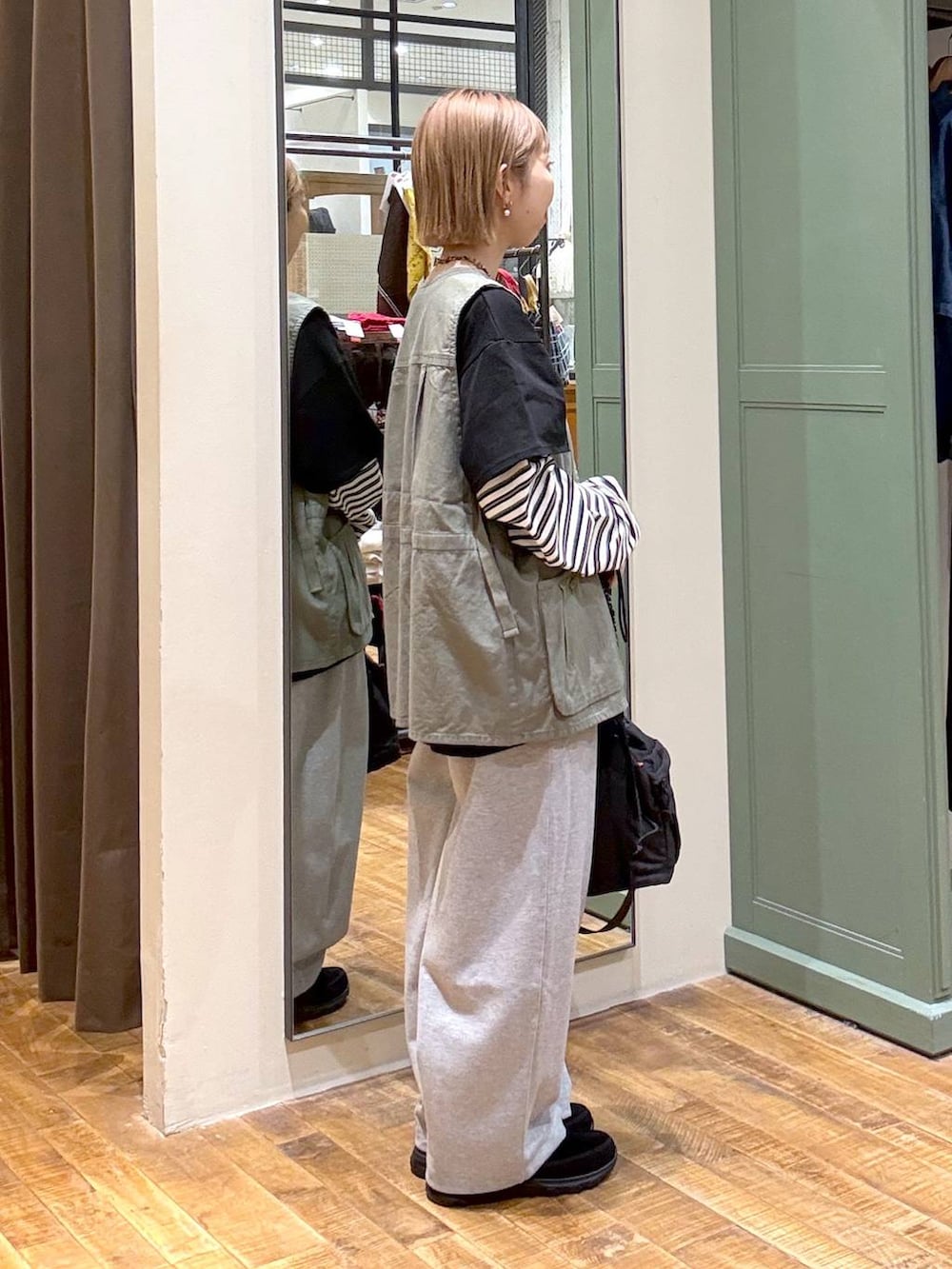 グリーン系のベスト、グレー系のスウェットパンツ、ブラック系のその他シューズを着用したレディースの春コーディネートの2枚目の写真