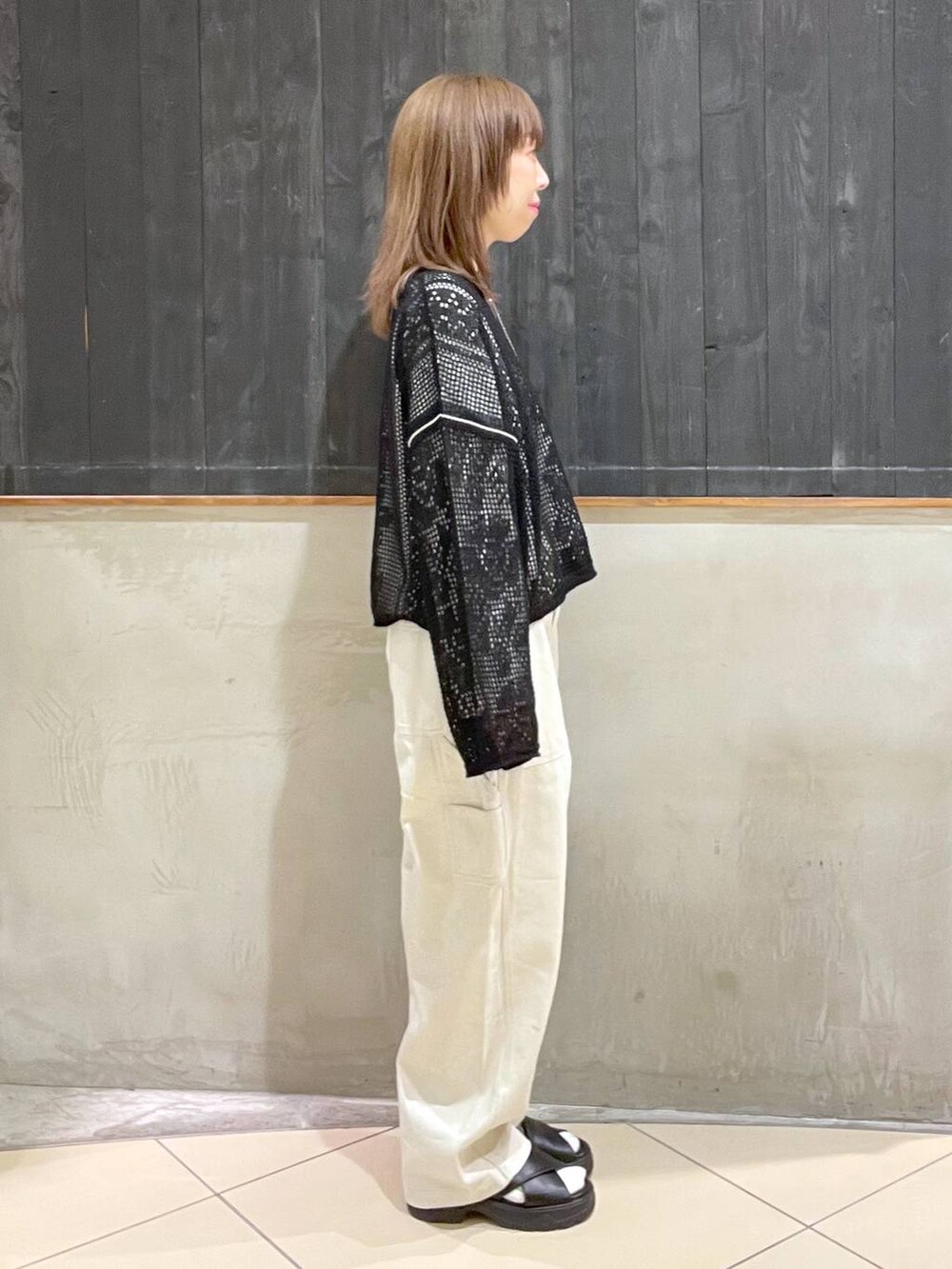 ブラック系のサンダル、ブラック系のニット/セーター、ブラック系のショルダーバッグを着用したレディースの春コーディネートの2枚目の写真