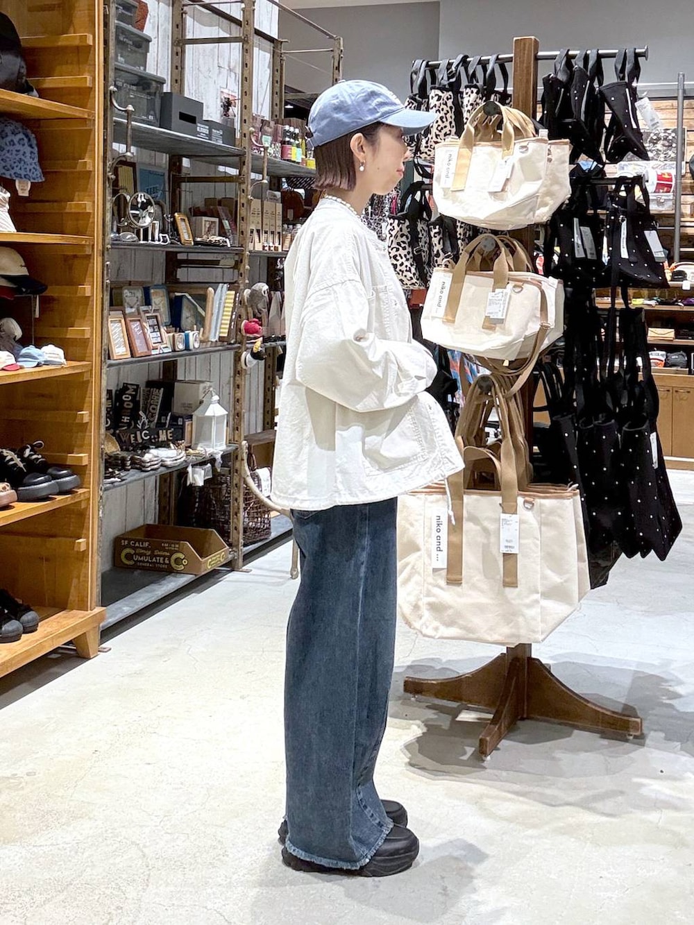 ベージュ系のカバーオール、ブルー系のデニムパンツ、ブラック系のボディバッグ/ウエストポーチを着用したレディースの春コーディネートの2枚目の写真