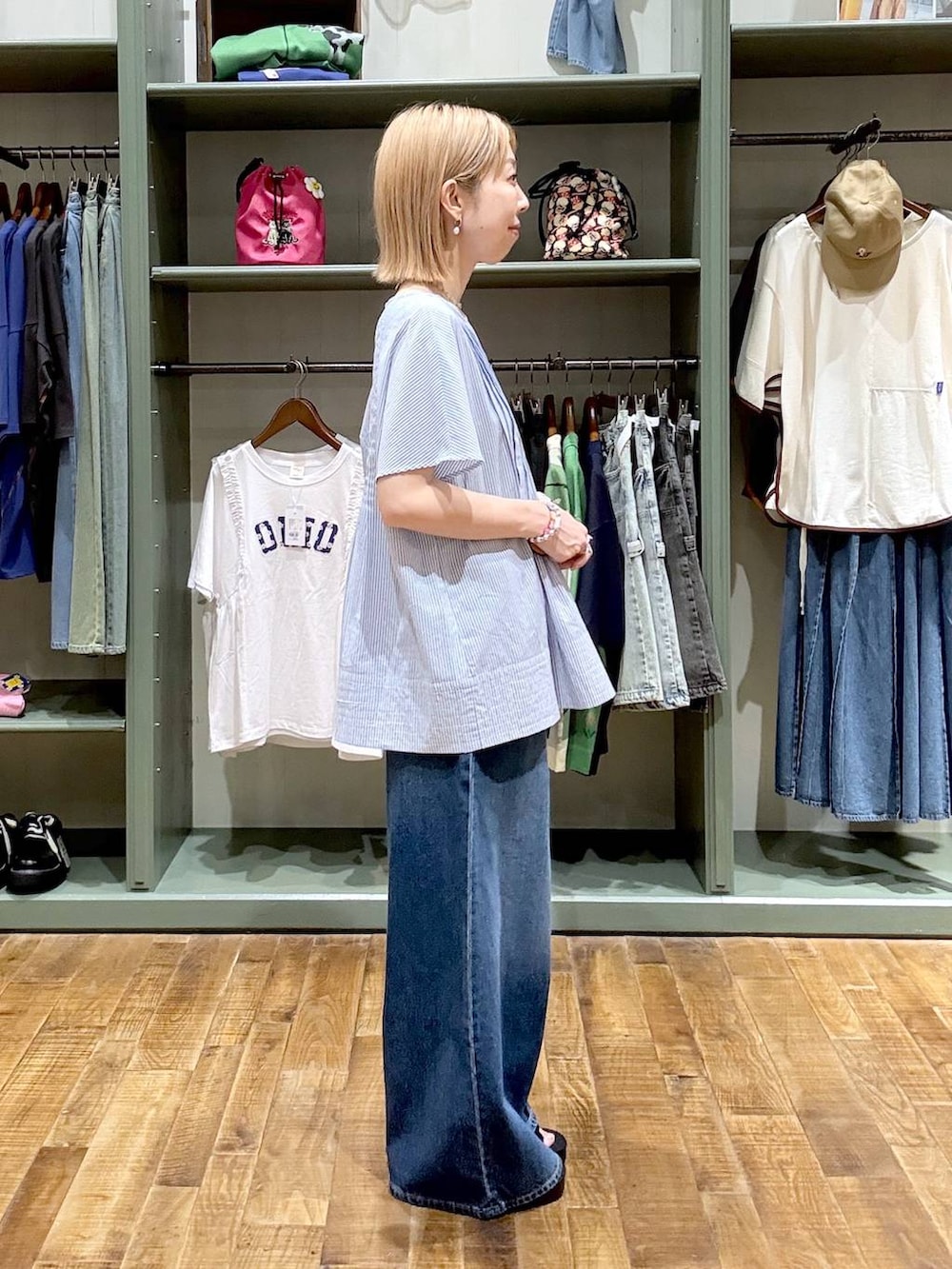 ブラック系のショルダーバッグ、ブルー系のデニムパンツ、ブラック系のサンダルを着用したレディースの夏コーディネートの2枚目の写真