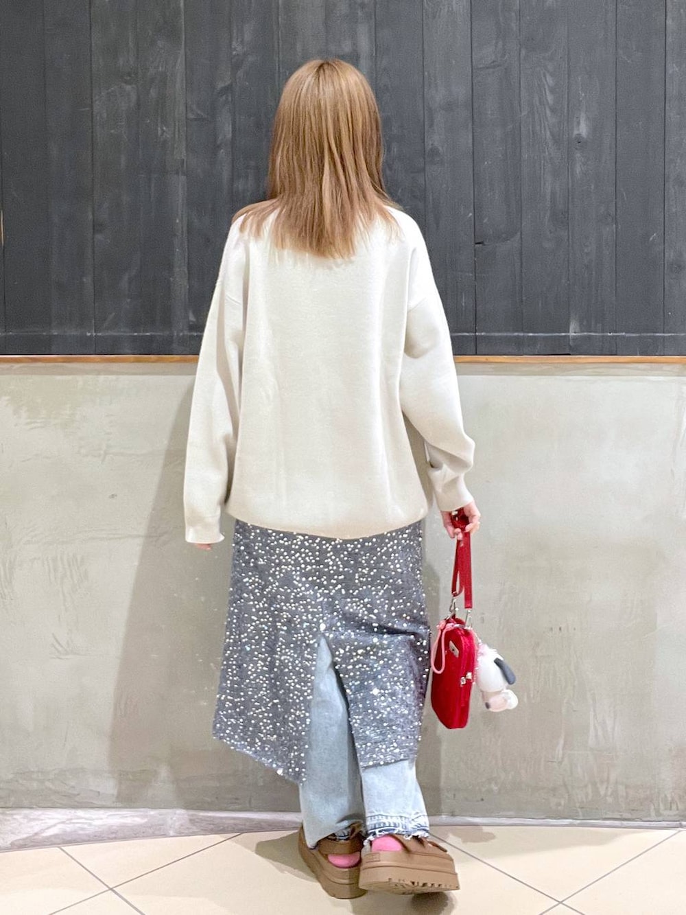 グレー系のスカート、レッド系のショルダーバッグ、ブルー系のデニムパンツを着用したレディースの春コーディネートの3枚目の写真