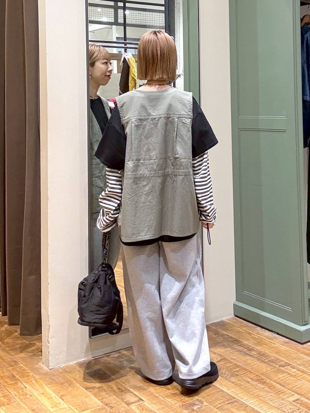 グリーン系のベスト、グレー系のスウェットパンツ、ブラック系のその他シューズを着用したレディースの春コーディネートの3枚目の写真