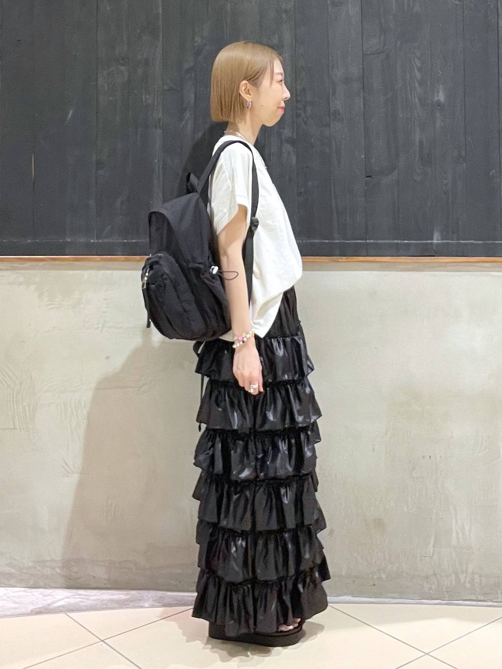 ブラック系のサンダル、ベージュ系のTシャツ/カットソー、ブラック系のバックパック/リュックを着用したレディースの夏コーディネートの2枚目の写真