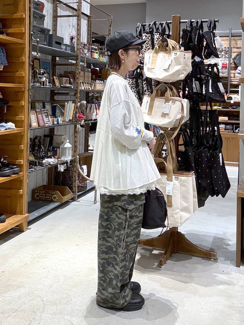 ブラック系のショルダーバッグ、ホワイト系のベスト、ブラック系のキャップを着用したレディースの春コーディネートの2枚目の写真