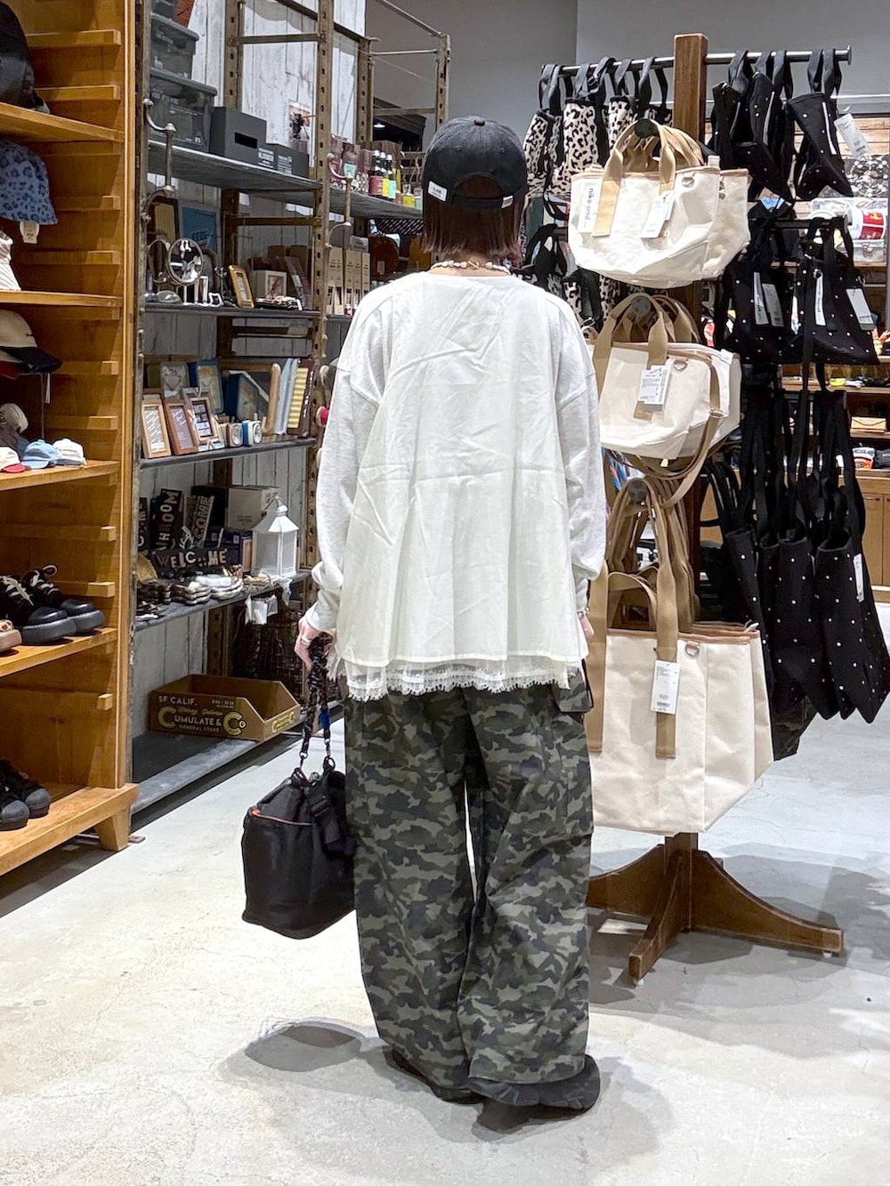 ブラック系のショルダーバッグ、ホワイト系のベスト、ブラック系のキャップを着用したレディースの春コーディネートの3枚目の写真