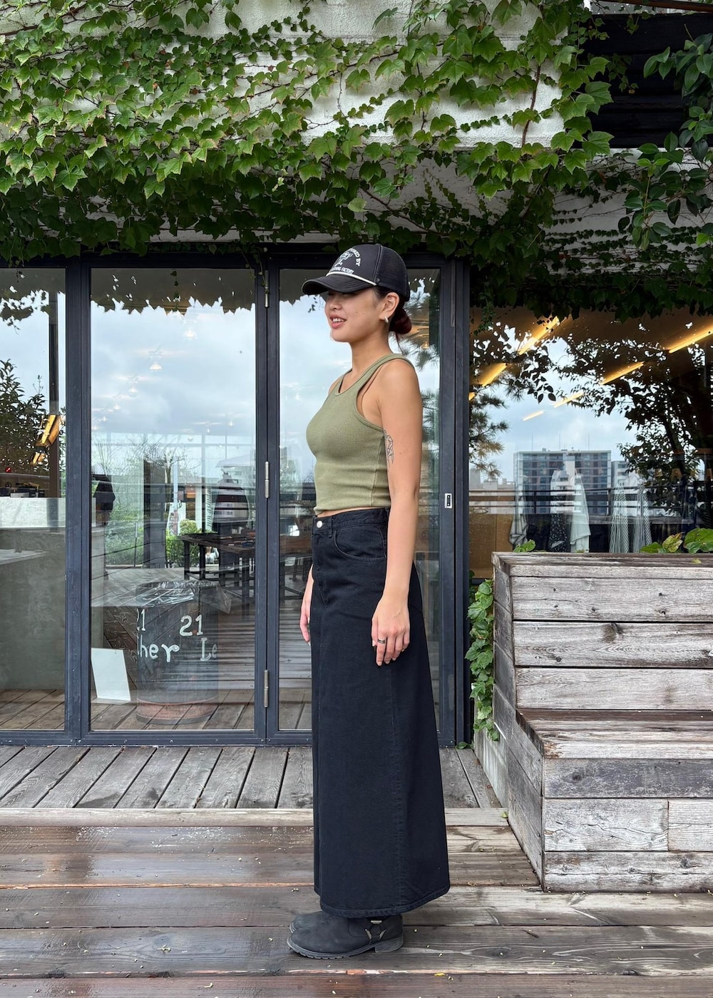 グリーン系のタンクトップ、ブラック系のデニムスカートを着用したレディースの秋コーディネートの2枚目の写真