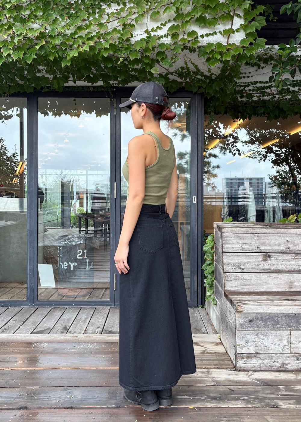 グリーン系のタンクトップ、ブラック系のデニムスカートを着用したレディースの秋コーディネートの3枚目の写真