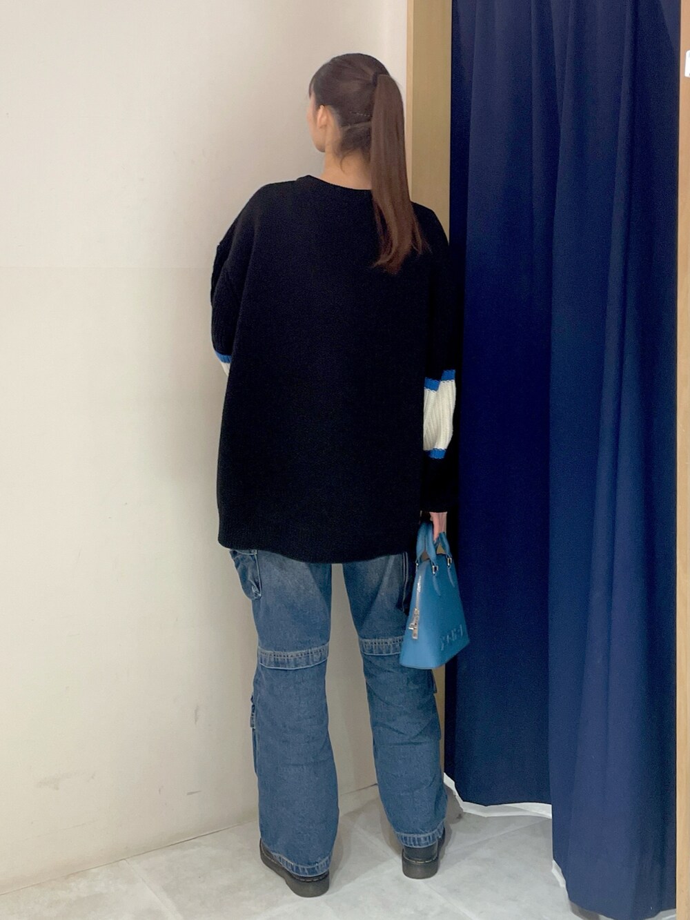 ブラック系のニット/セーター、ブルー系のデニムパンツ、ブルー系のショルダーバッグを着用したレディースの冬コーディネートの5枚目の写真