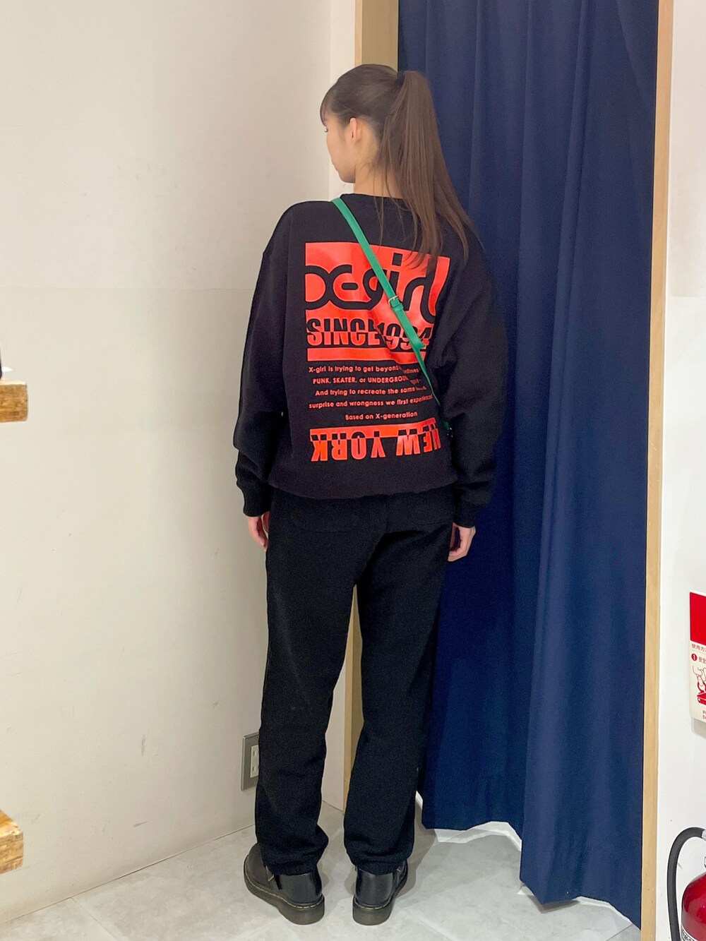 ブラック系のスウェット、グリーン系のショルダーバッグ、ブラック系のスウェットパンツを着用したレディースの冬コーディネートの2枚目の写真