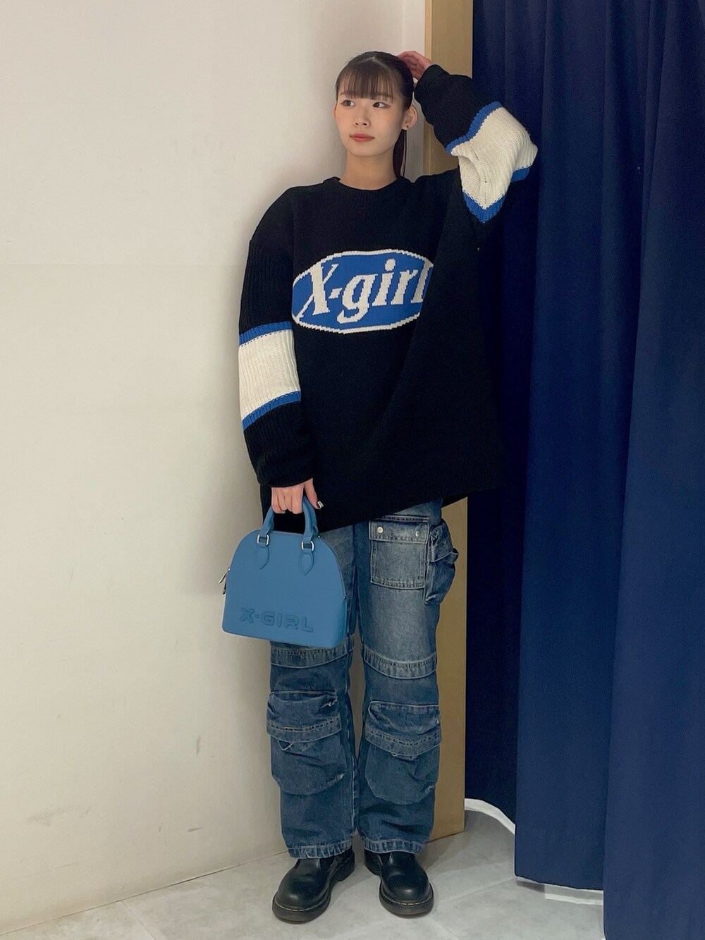 ブラック系のニット/セーター、ブルー系のデニムパンツ、ブルー系のショルダーバッグを着用したレディースの冬コーディネートの2枚目の写真