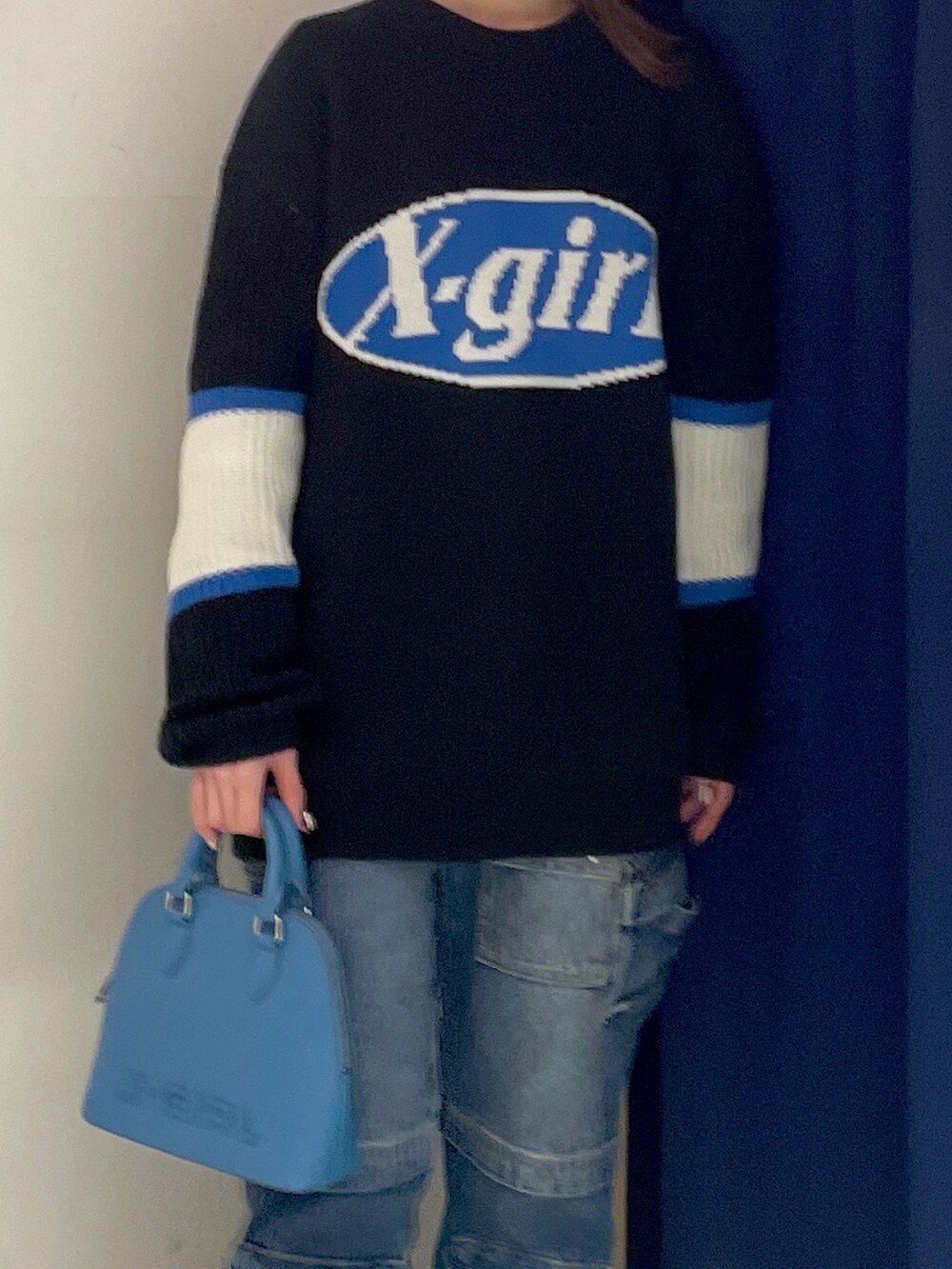 ブラック系のニット/セーター、ブルー系のデニムパンツ、ブルー系のショルダーバッグを着用したレディースの冬コーディネートの3枚目の写真