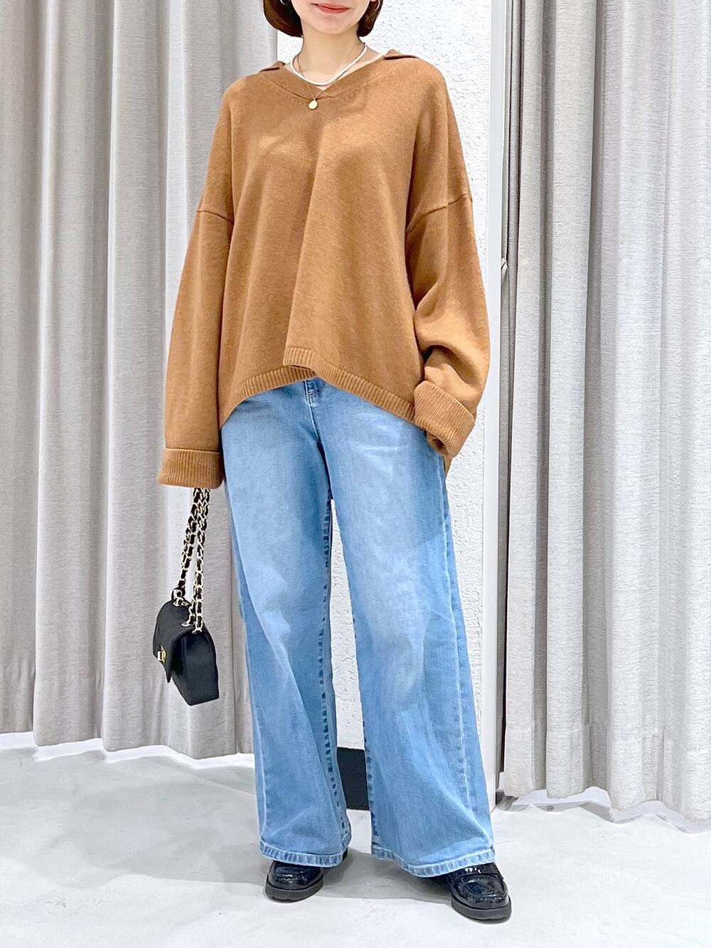 ブルー系のデニムパンツ、イエロー系のニット/セーター、ブラック系のショルダーバッグを着用したレディースの冬コーディネートの2枚目の写真