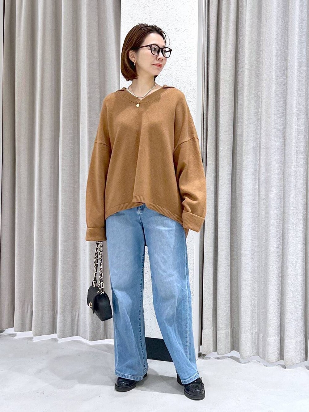 ブルー系のデニムパンツ、イエロー系のニット/セーター、ブラック系のショルダーバッグを着用したレディースの冬コーディネートの8枚目の写真