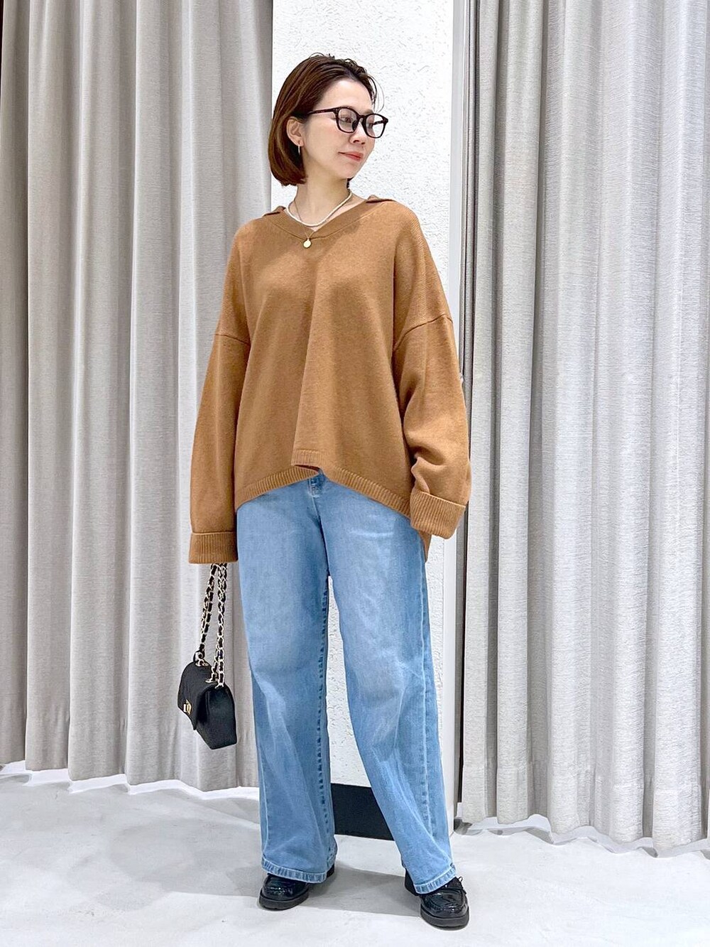 ブルー系のデニムパンツ、イエロー系のニット/セーター、ブラック系のショルダーバッグを着用したレディースの冬コーディネートの4枚目の写真