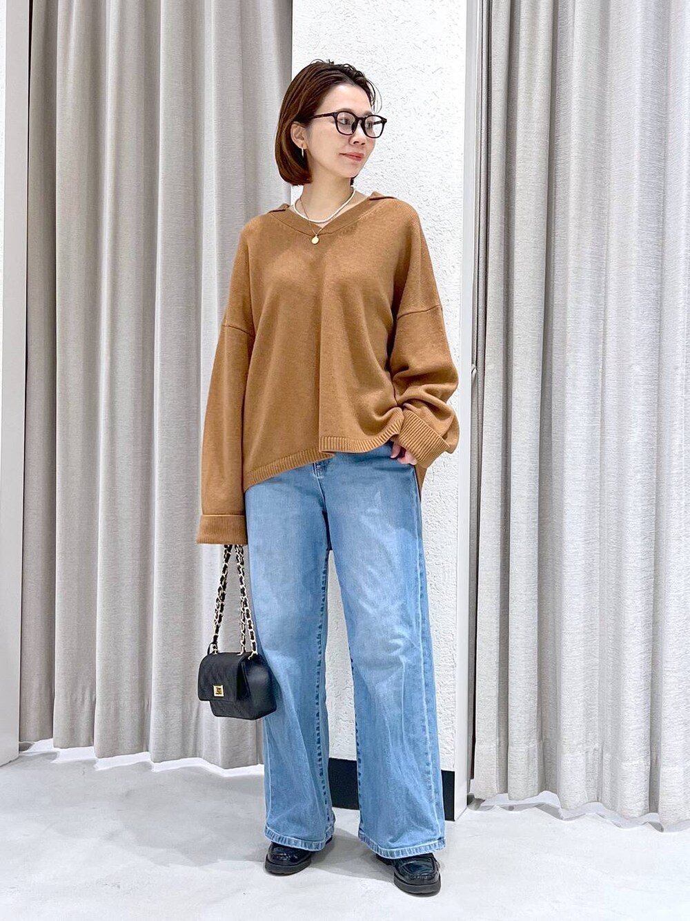 ブルー系のデニムパンツ、イエロー系のニット/セーター、ブラック系のショルダーバッグを着用したレディースの冬コーディネートの5枚目の写真
